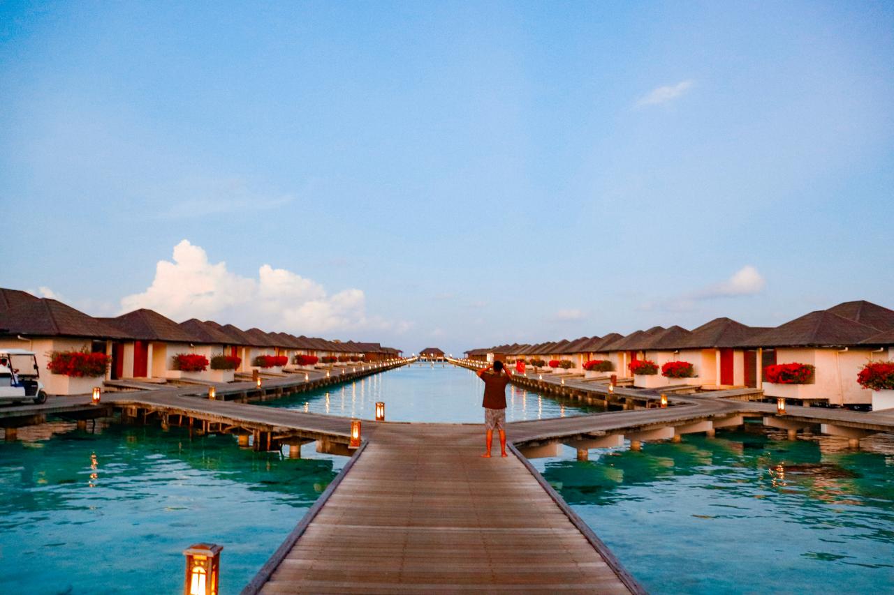 Bungalow di atas air berjejer di laut biru kehijauan yang indah.